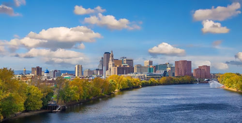 Buildings by river against sky