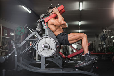 Full length of man with arms raised leg workout in gym