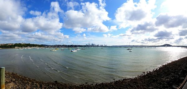 Boats in sea against cloudy sky