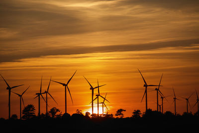 Silhouette cranes against sky during sunset