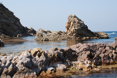 Rocks on beach against clear sky