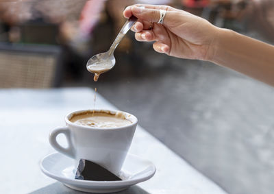 Cropped image of hand pouring coffee in cup