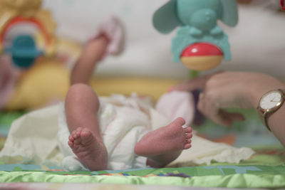 Cropped hand of woman with baby lying on bed