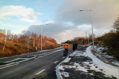 Vehicles on road against sky during winter