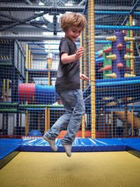 Full length of happy boy jumping over trampoline