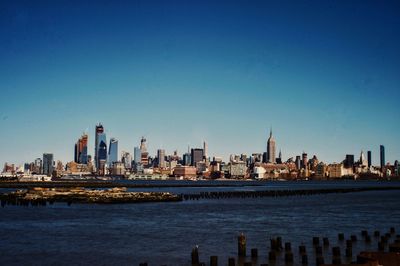 City at waterfront against blue sky