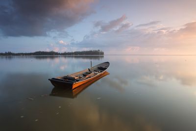 Fishing boat moored on lake during sunset