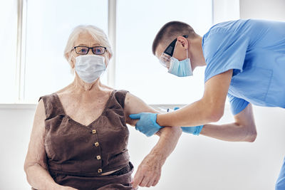 Doctor wearing mask vaccinating patient