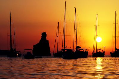 Silhouette sailboats sailing in sea against sky during sunset