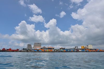 City at waterfront against cloudy sky