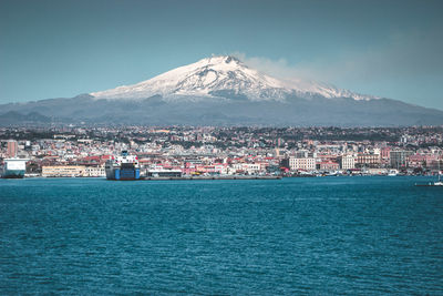 Scenic view of sea by city against sky during winter