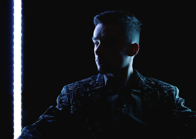 Portrait of young man against black background