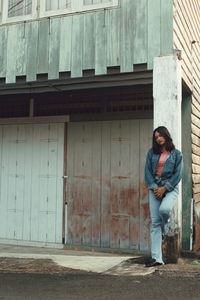 Portrait of young woman standing outside building in city