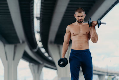 Full length of shirtless man sitting outdoors