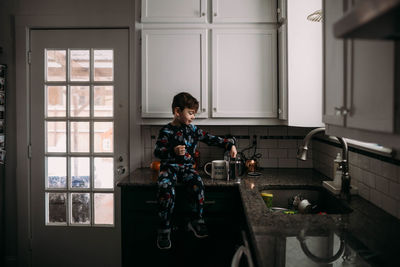 Young boy in kitchen learning to make coffee in morning time