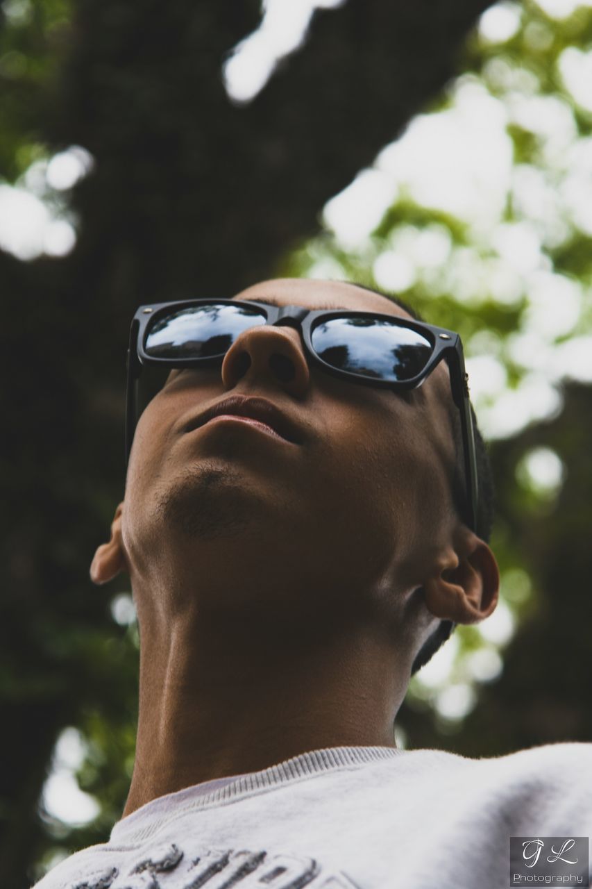 sunglasses, real people, one person, focus on foreground, day, young adult, headshot, young men, leisure activity, outdoors, tree, lifestyles, close-up