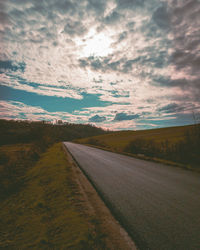 Road amidst field against sky