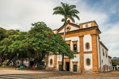 Overview of old colored church, garden with trees and cobblestone street in paraty, brazil