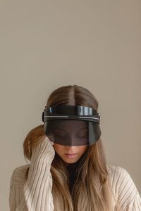 Young woman wearing headwear against beige background