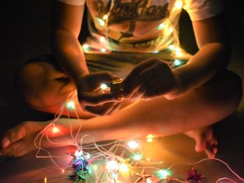 Midsection of woman holding illuminated candles