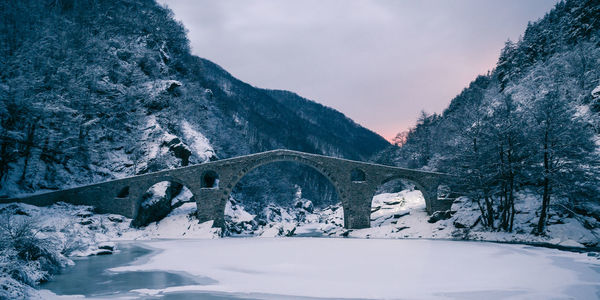 Bridge over snowcapped mountains against sky
