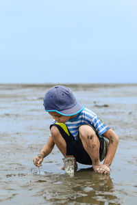 Full length of boy playing with sand at beach