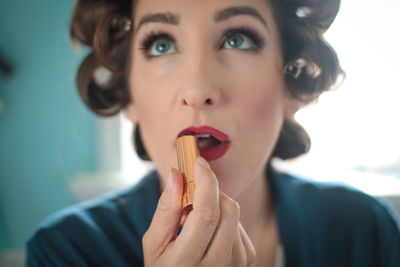 Close-up of woman applying red lipstick at home