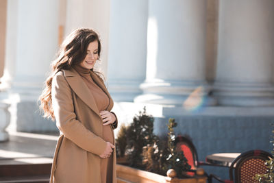 Smiling pregnant woman standing on street