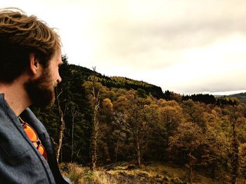 Young man standing on landscape against sky