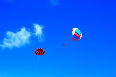 Low angle view of hot air balloons flying against blue sky