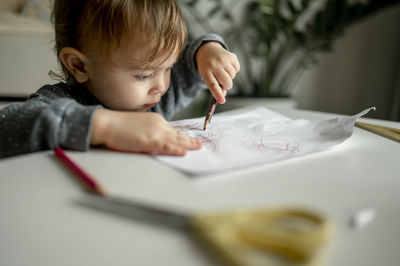 Boy drawing on paper with colored pencil at home