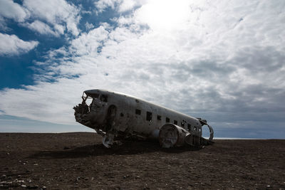 Abandoned airplane on airport runway against sky