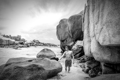 People on rock at beach against sky