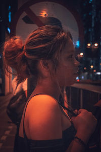 Portrait of woman looking at illuminated nightclub