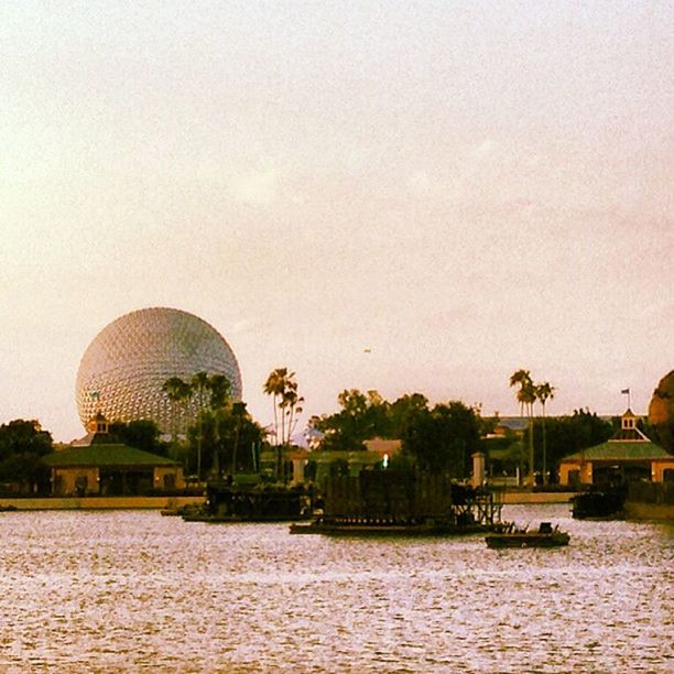 architecture, built structure, waterfront, water, building exterior, tree, river, sky, clear sky, rippled, sea, copy space, ferris wheel, nature, sunset, outdoors, tranquility, tranquil scene, travel destinations, scenics