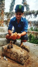 Portrait of smiling young man sitting on rock