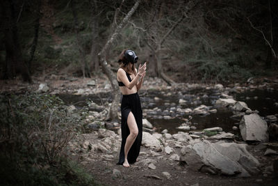 Side view of sensuous woman wearing gas mask while standing in forest