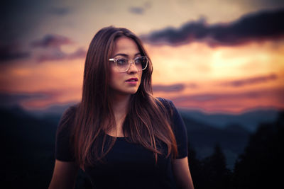 Portrait of beautiful young woman against sunset sky