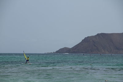 Man surfing in sea against clear sky