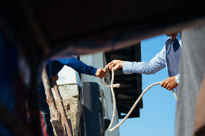 Midsection of people holding rope outdoors