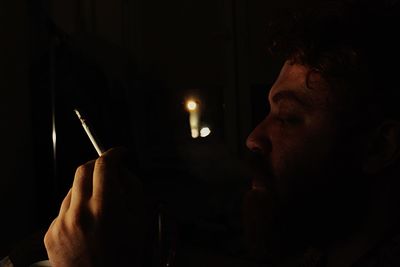 Close-up of man smoking cigarette at night