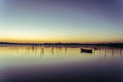 View of pier in sea at sunset