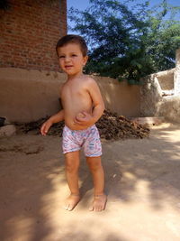 Full length of shirtless boy standing outdoors