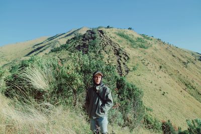 Young man standing against mountain and sky