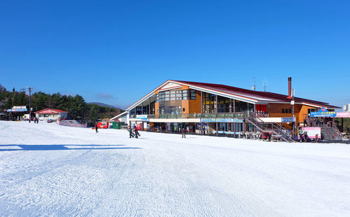 Built structure in winter against clear blue sky