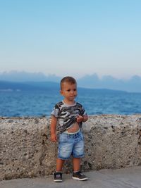 Baby boy standing on promenade against blue sky during sunset