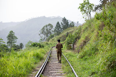 Rear view of person on railroad track against sky