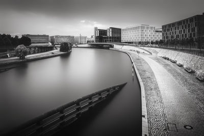 High angle view of canal by sidewalk in city against sky