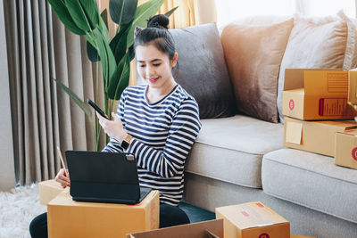 Young woman using laptop while sitting on sofa at home