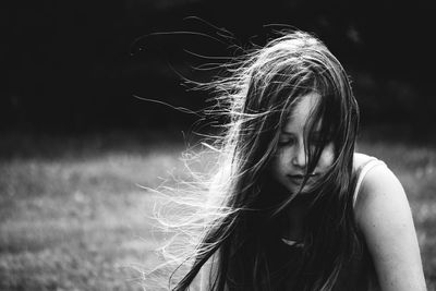 Girl with tousled hair sitting on field